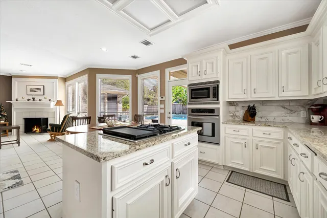 a kitchen with stainless steel appliances granite countertop a stove a sink and a granite counter tops with white cabinets