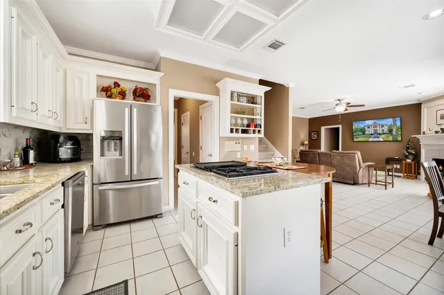 a kitchen with stainless steel appliances granite countertop a stove top oven a sink a refrigerator and white cabinets