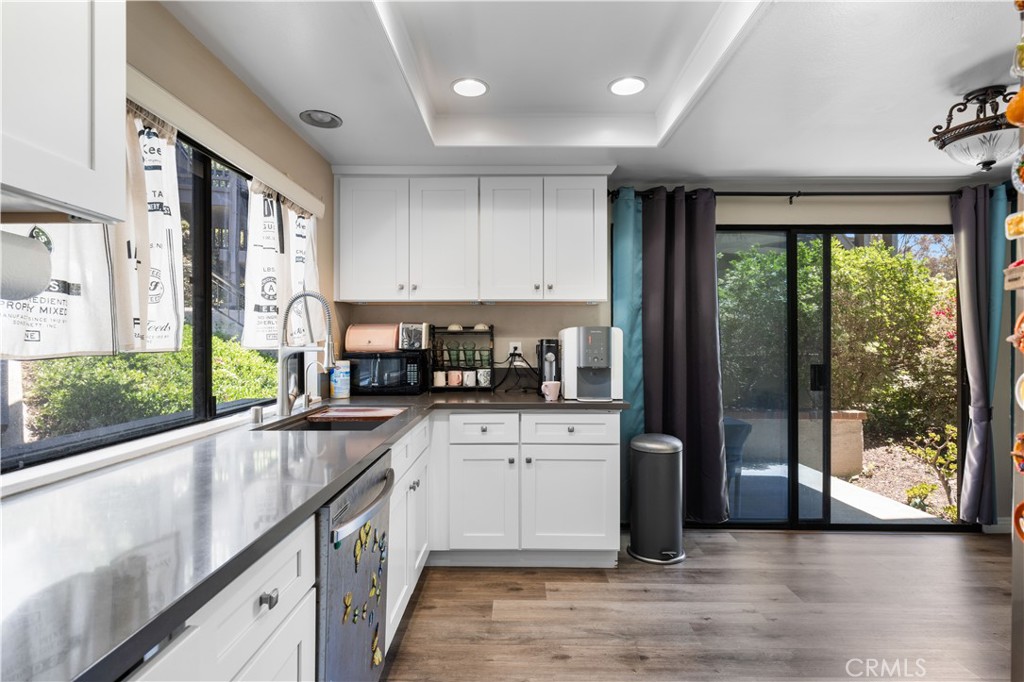 11 Palos, Unit 55 Irvine, CA 92612 - Photo 7 of 25 a kitchen with stainless steel appliances granite countertop a refrigerator a sink dishwasher a stove and a dining table with wooden floor