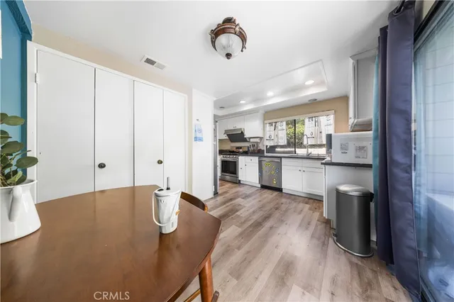 a kitchen with stainless steel appliances granite countertop a stove top oven a sink dishwasher and a refrigerator with wooden floor