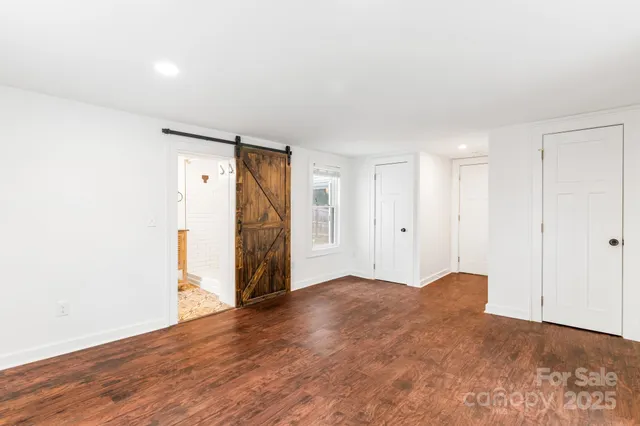 a view of an empty room with wooden floor and closet area