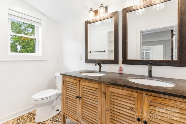 a bathroom with a granite countertop toilet a sink and a mirror