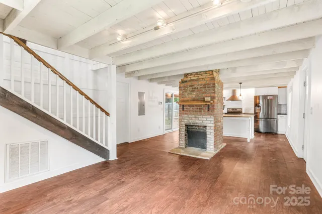 a view of a livingroom with a fireplace wooden floor and staircase