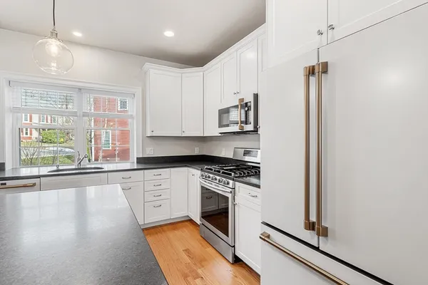 a kitchen with stainless steel appliances granite countertop a stove a sink and a refrigerator with wooden floors
