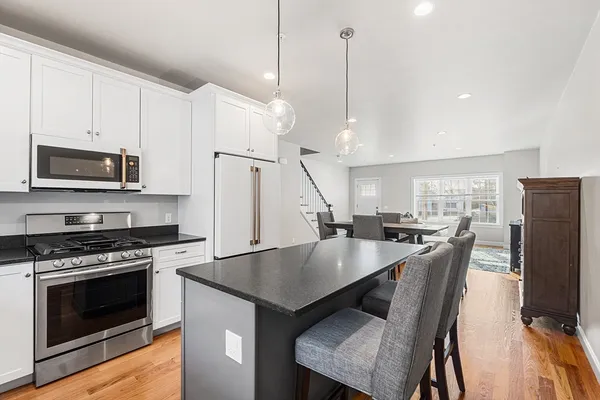 a kitchen with stainless steel appliances a stove a microwave a dining table and chairs