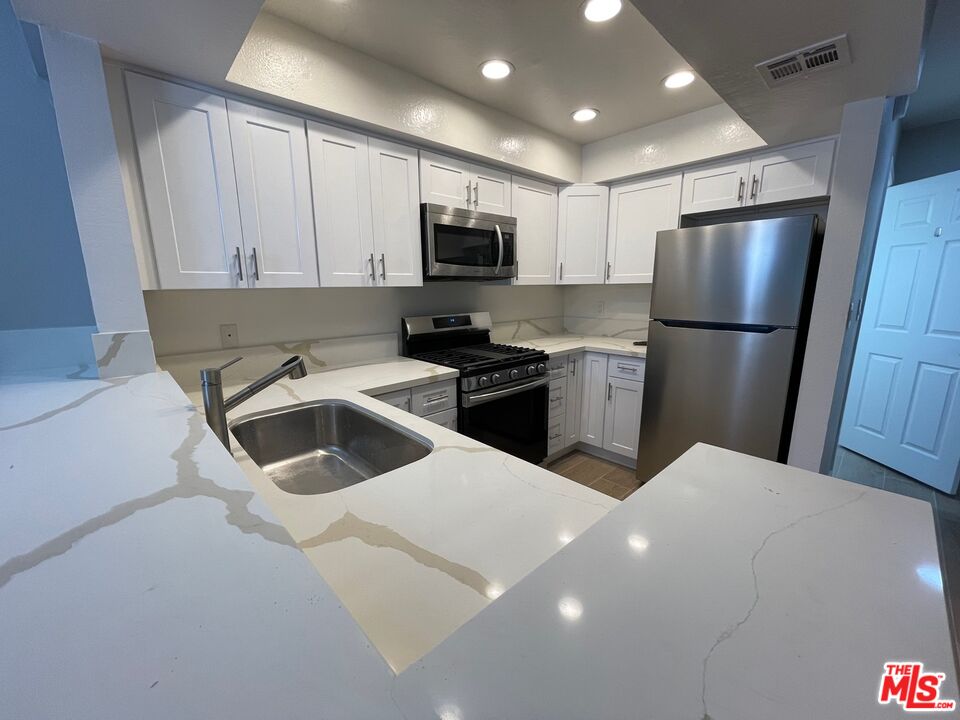 7327 Willoughby Avenue, Unit 6 Los Angeles, CA 90046 - Photo 15 of 24 a kitchen with a sink a refrigerator a microwave and cabinets