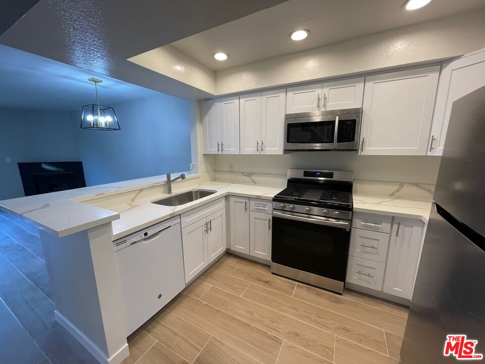 7327 Willoughby Avenue, Unit 6 Los Angeles, CA 90046 - Photo 16 of 24 a kitchen with granite countertop a sink and steel appliances