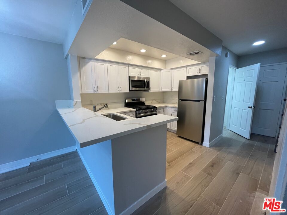 7327 Willoughby Avenue, Unit 6 Los Angeles, CA 90046 - Photo 17 of 24 a kitchen with a refrigerator a stove top oven a sink and cabinets