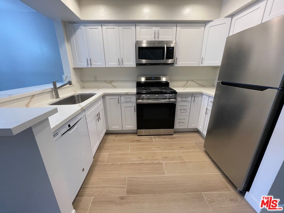 7327 Willoughby Avenue, Unit 6 Los Angeles, CA 90046 - Photo 18 of 24 a kitchen with stainless steel appliances a refrigerator sink and microwave
