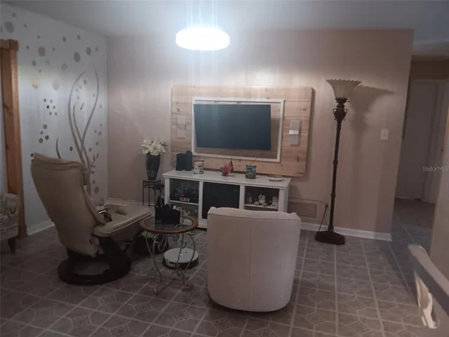 a living room with furniture a flat screen tv and kitchen view