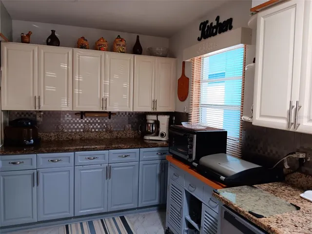 a kitchen with granite countertop a sink a stove and cabinets