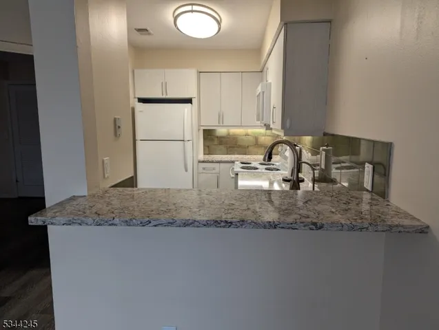 a kitchen with kitchen island granite countertop a sink a stove a refrigerator and cabinets