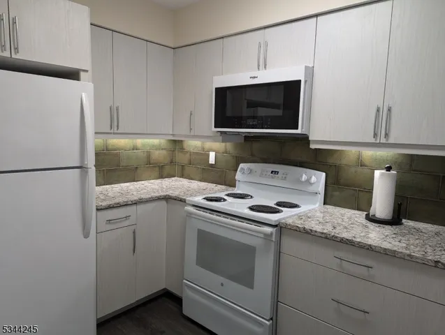 a kitchen with granite countertop white cabinets and white appliances