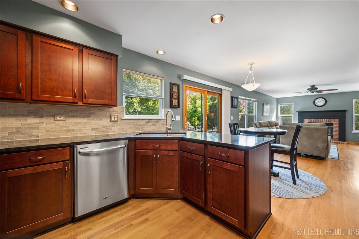 1244 Churchill Road Bartlett, IL 60103 - Photo 13 of 33 a kitchen with stainless steel appliances granite countertop wooden cabinets a dining table and chairs next to a window