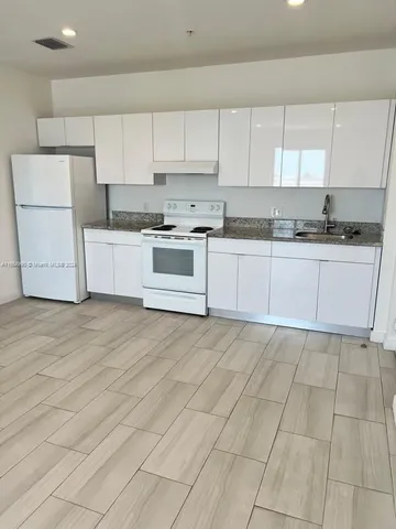 a kitchen with stainless steel appliances granite countertop a stove a sink and white cabinets