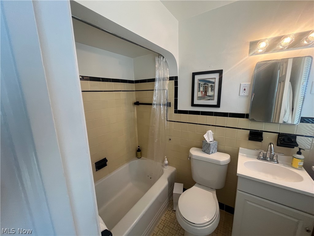3471 Warren Road Cleveland, OH 44111 - Photo 14 of 17 Full bathroom featuring vanity, shower / tub combo, tile walls, and a wainscoted wall