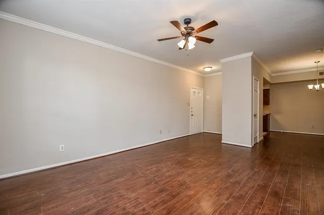 an empty room with wooden floor and a ceiling fan