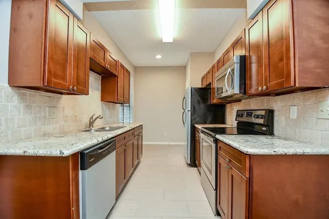 a kitchen with stainless steel appliances granite countertop a sink stove and cabinets
