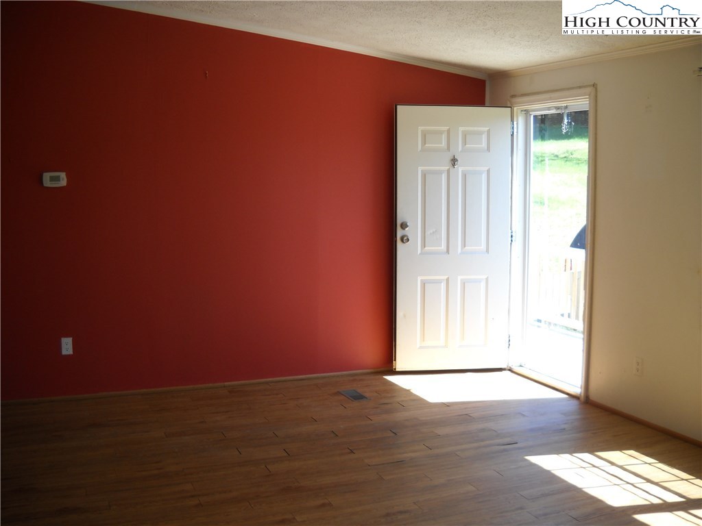 605 Wagoner Ridge Road Ennice, NC 28623 - Photo 3 of 5 a view of an empty room with wooden floor and a window