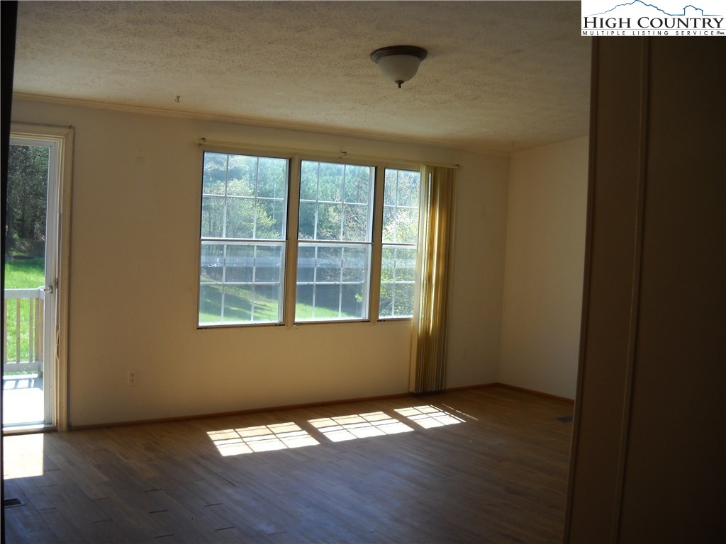 605 Wagoner Ridge Road Ennice, NC 28623 - Photo 4 of 5 a view of an empty room with wooden floor and a window
