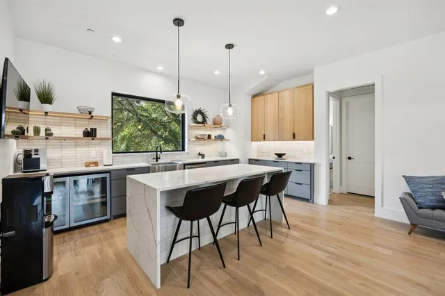 a open kitchen with stainless steel appliances granite countertop a stove a sink dishwasher and a dining table with wooden floor