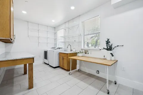 a large white kitchen with a sink and a stove top oven