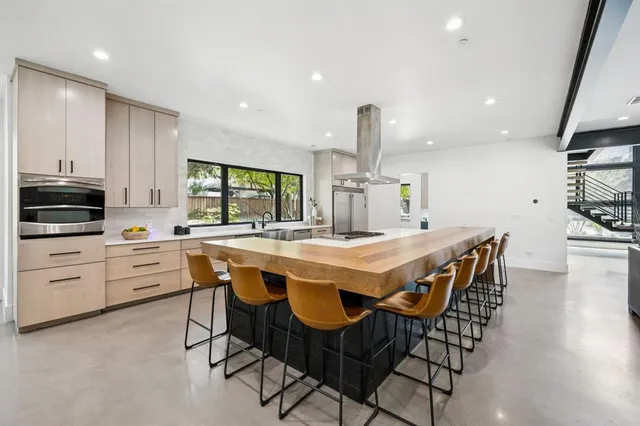 a kitchen with stainless steel appliances kitchen island granite countertop a stove a sink and a refrigerator