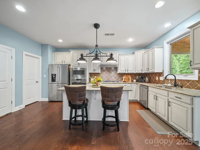 a kitchen with stainless steel appliances granite countertop a white cabinets and wooden floor