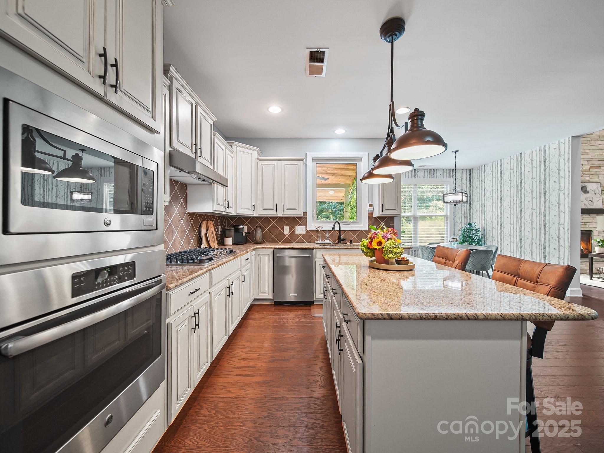 9639 Estridge Lane Concord, NC 28027 - Photo 19 of 48 a kitchen with stainless steel appliances granite countertop a sink dishwasher a stove and white cabinets with wooden floor