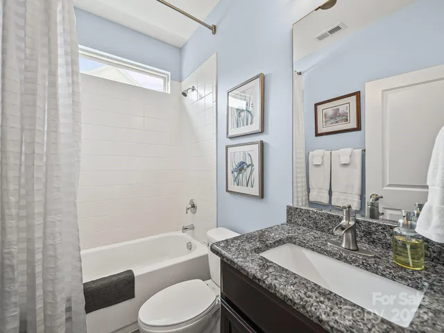 a bathroom with a granite countertop tub sink toilet and mirror
