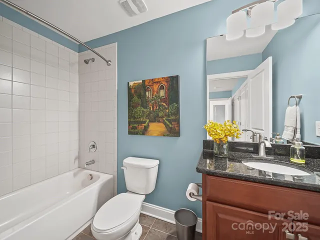 a bathroom with a granite countertop bathtub sink vanity mirror and toilet