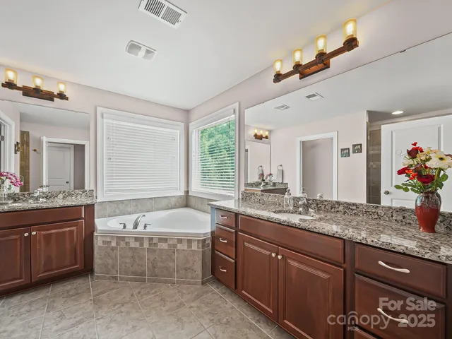 a bathroom with a granite countertop double vanity sink and a bathtub