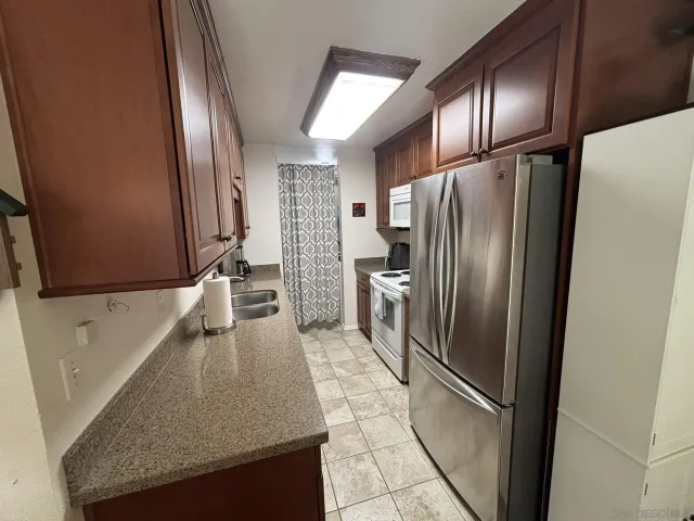 a kitchen with granite countertop a refrigerator and a sink