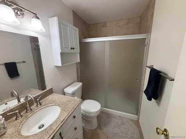 a bathroom with a granite countertop sink toilet and shower