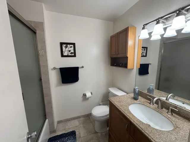 a bathroom with a granite countertop toilet sink and mirror