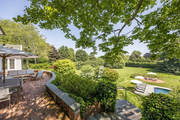 a view of a garden with lawn chairs under an umbrella