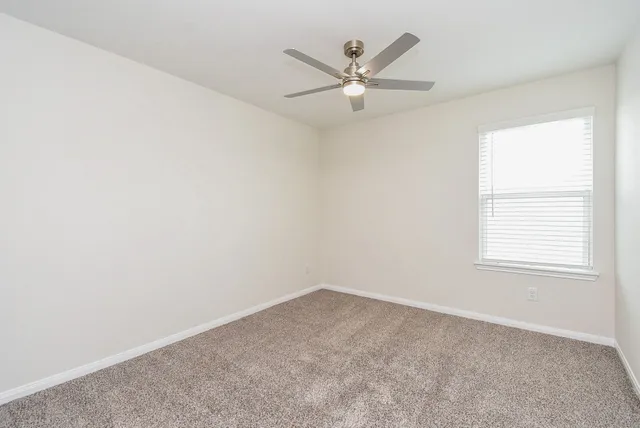 an empty room with a window and a fan