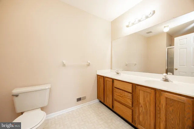 a bathroom with a double vanity sink toilet and mirror