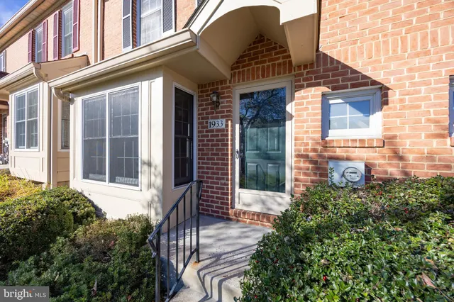 a view of a brick house with large windows and a flower plants