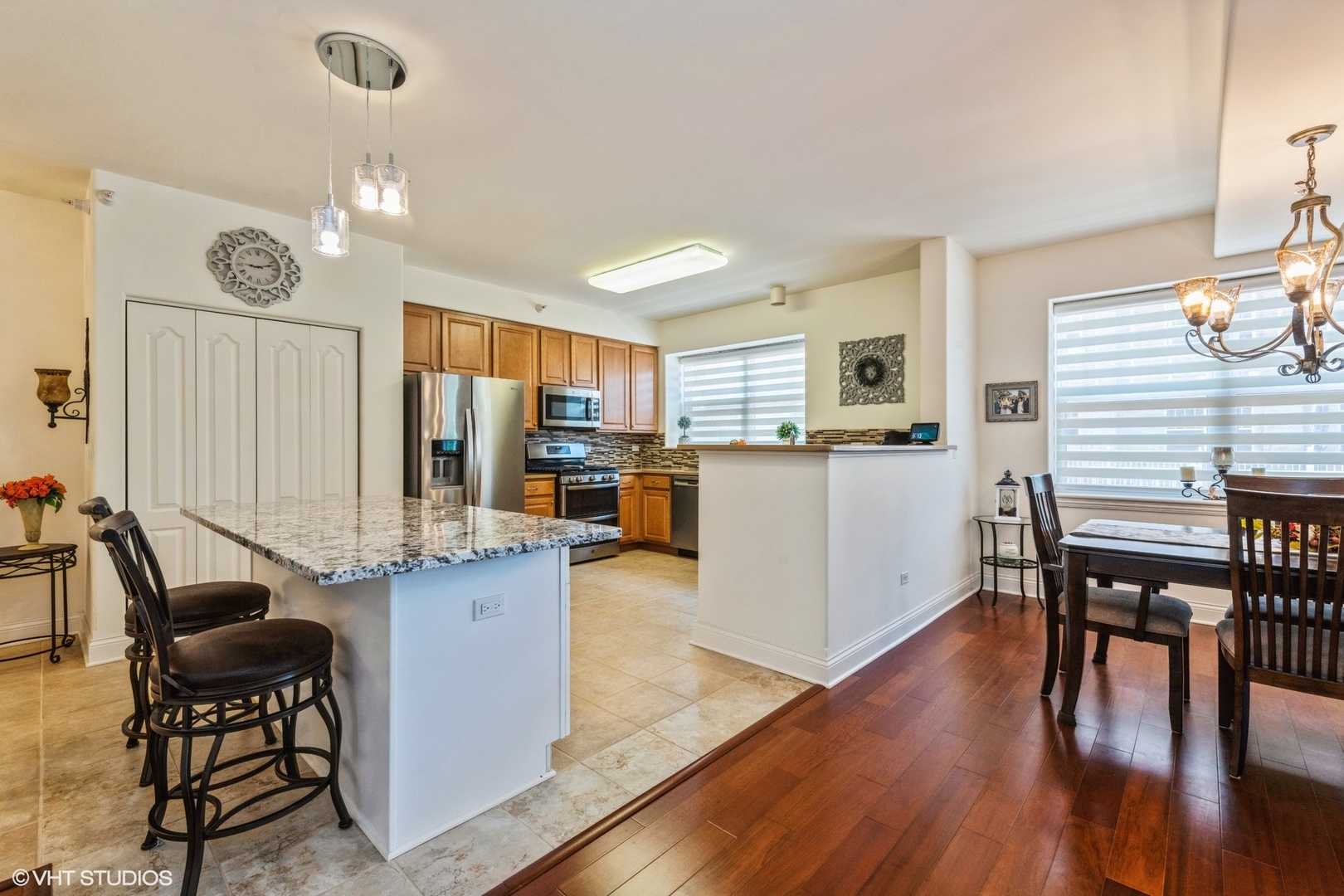 1 Itasca Road, Unit 101 Itasca, IL 60143 - Photo 5 of 21 a kitchen with stainless steel appliances kitchen island granite countertop a table chairs and a refrigerator