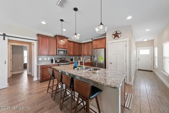 a kitchen with stainless steel appliances granite countertop a stove a refrigerator a kitchen island a sink and a wooden cabinets