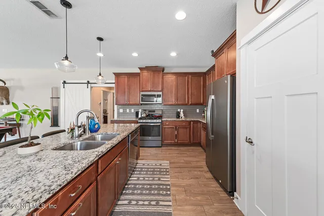 a kitchen with stainless steel appliances granite countertop a sink refrigerator and cabinets