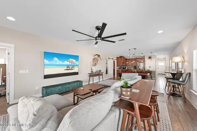 a living room with furniture a wooden floor and a ceiling fan