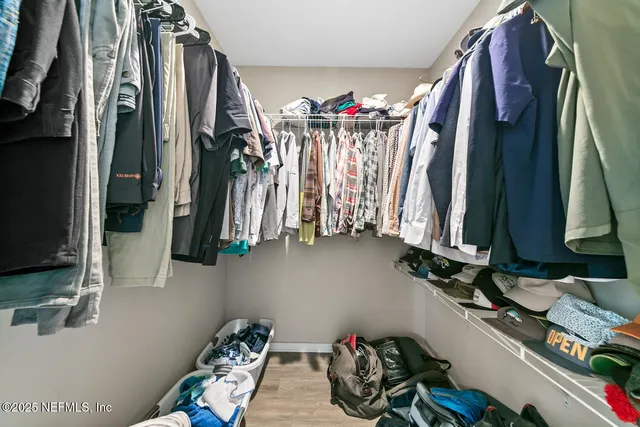 a view of walk in closet with clothes and shoes