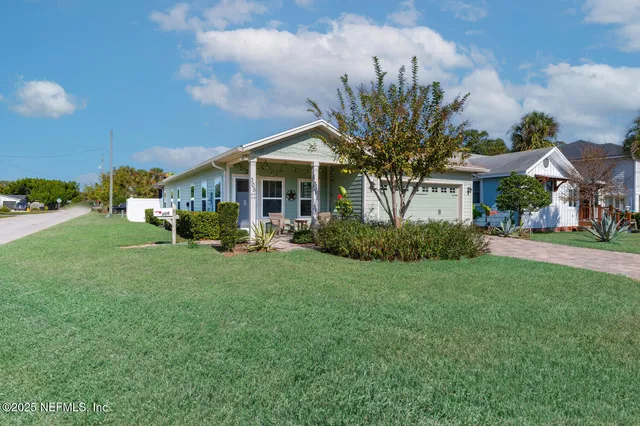 a view of a white house with a big yard and potted plants