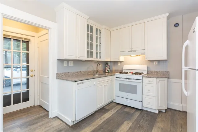 a kitchen with granite countertop white cabinets and white appliances