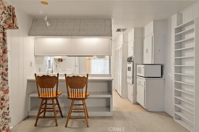 a kitchen with stainless steel appliances kitchen island granite countertop a refrigerator and a dining table