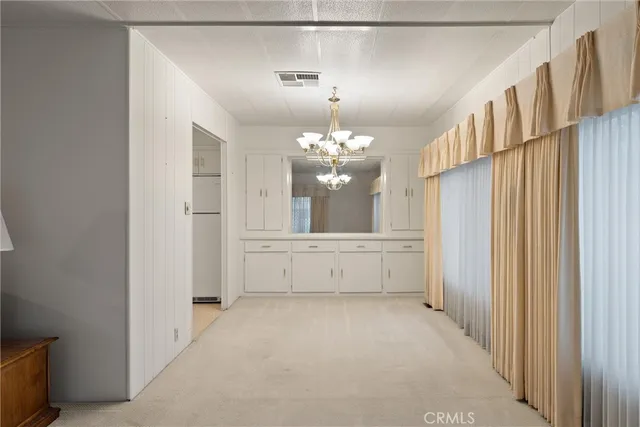 a view of a hallway with chandelier and a refrigerator