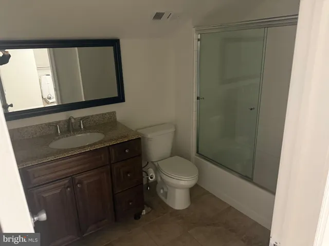 a bathroom with a granite countertop toilet and sink