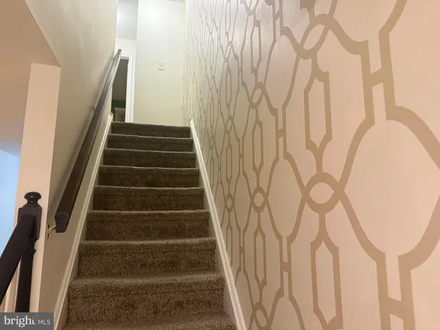 a view of staircase with wooden floor and white walls